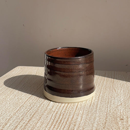 red ceramic cup on a textured surface with a neutral background