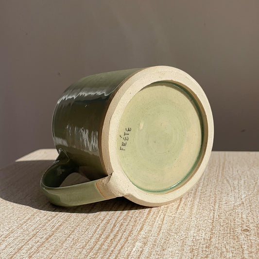 Green ceramic mug on a textured surface