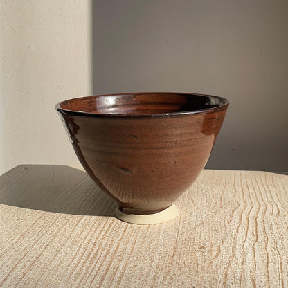 red ceramic bowl on a wooden surface with a neutral background
