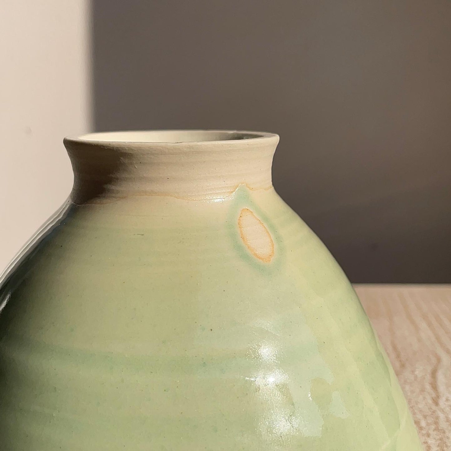 Green ceramic vase with a textured surface on a neutral background