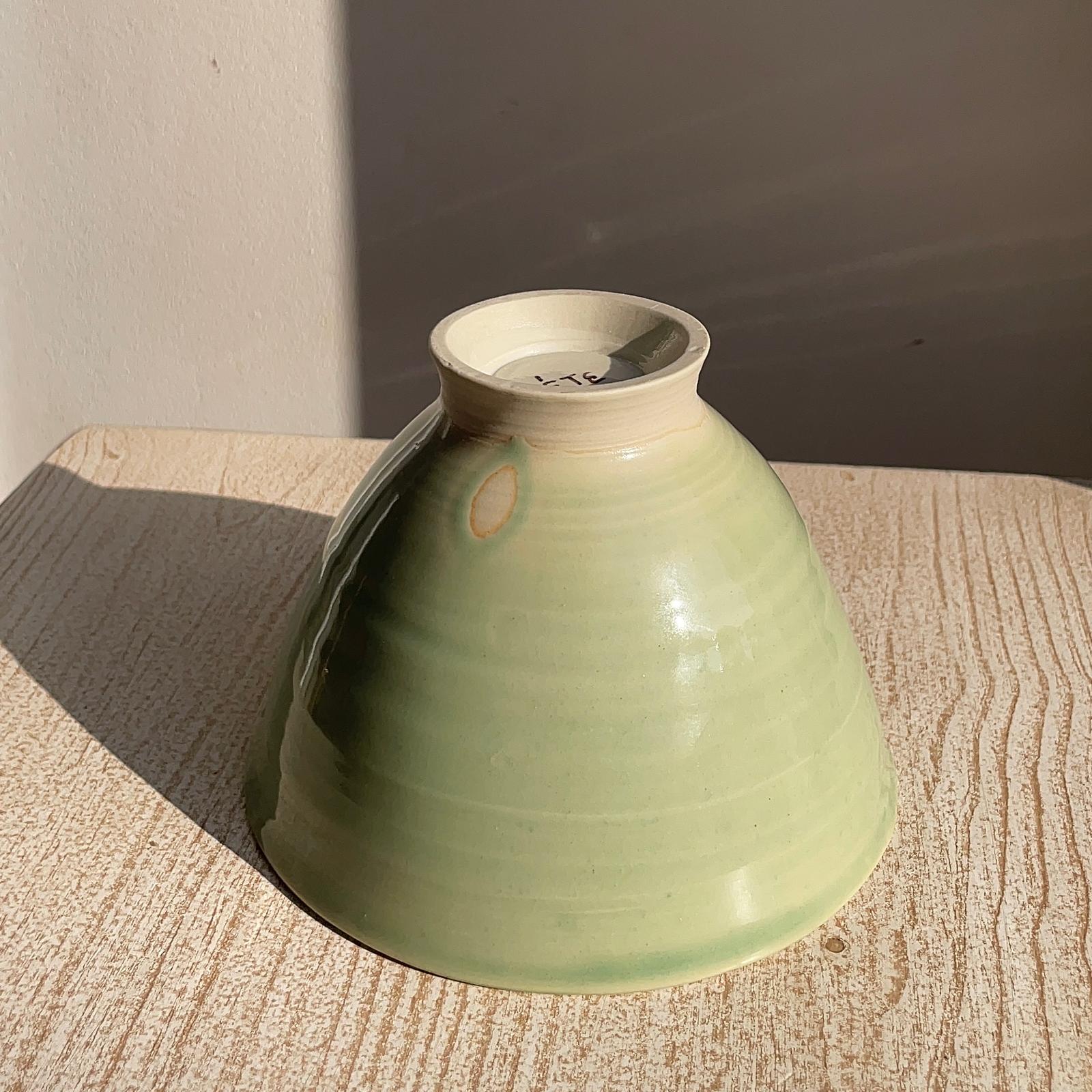 Green ceramic bowl on a wooden surface with a neutral background