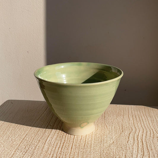 Green ceramic bowl on a textured surface with a neutral background