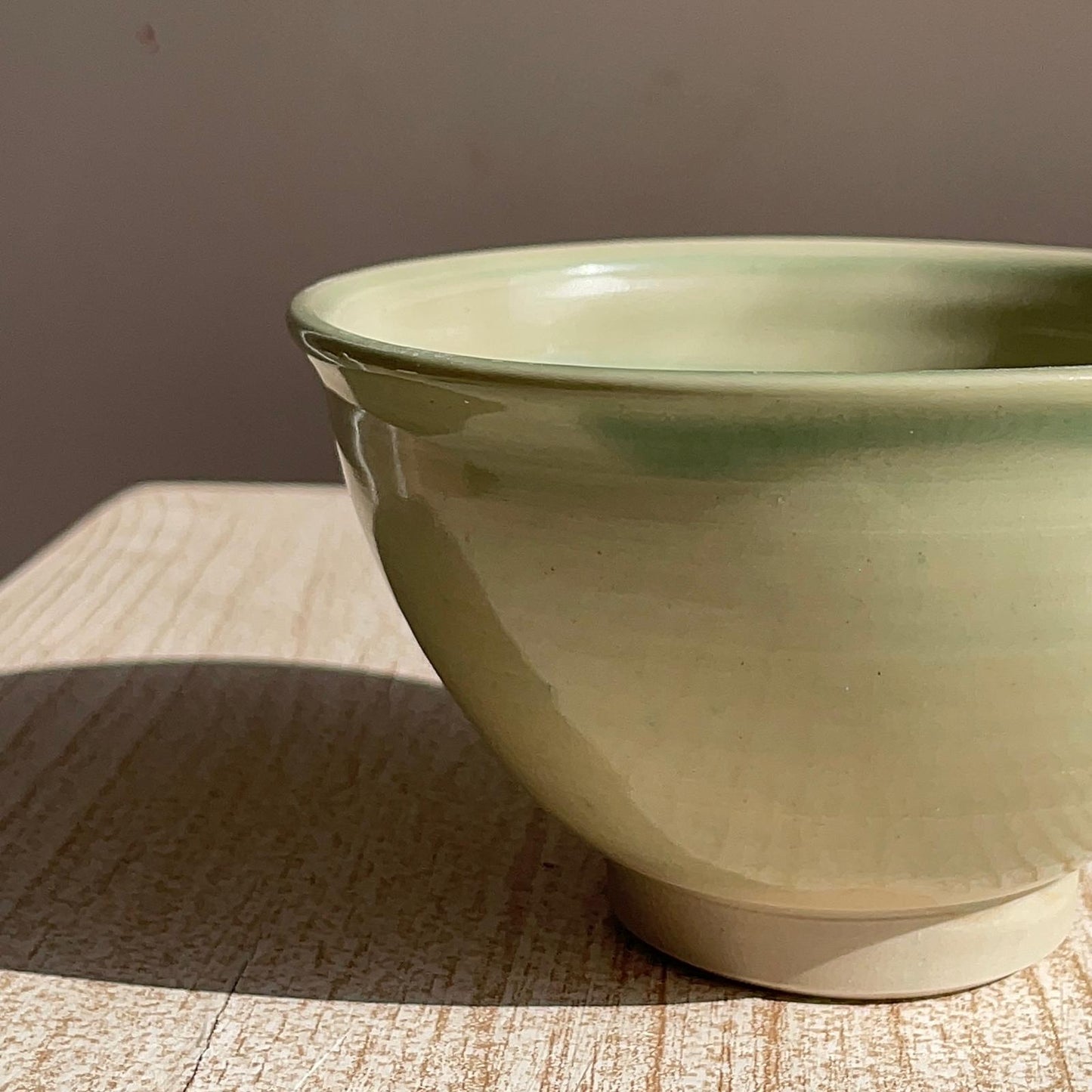 Green ceramic bowl on a textured surface with a neutral background