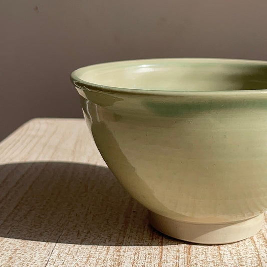 Green ceramic bowl on a textured surface with a neutral background
