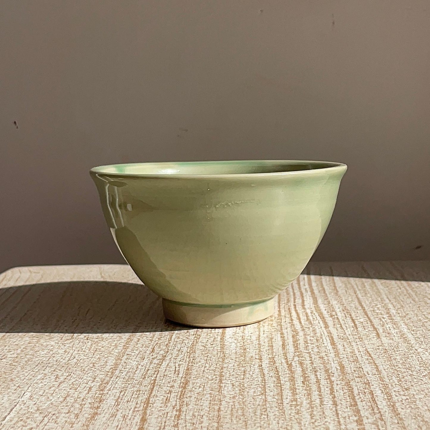 Green ceramic bowl on a textured surface with a neutral background