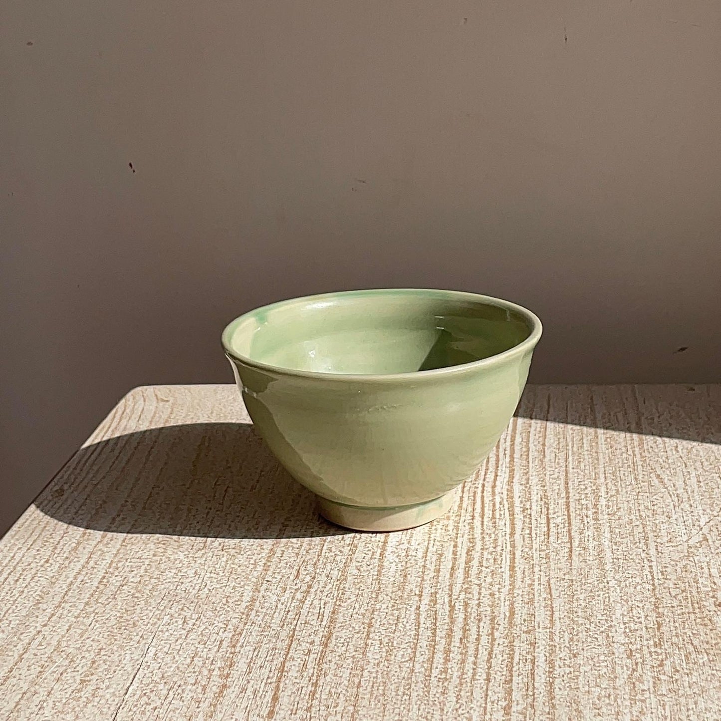 Green ceramic bowl on a textured surface with a neutral background