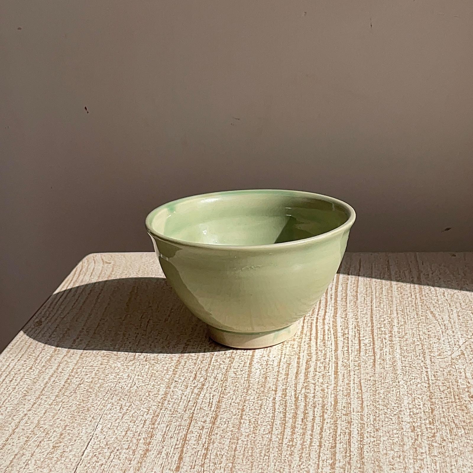 Green ceramic bowl on a textured surface with a neutral background