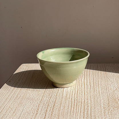 Green ceramic bowl on a textured surface with a neutral background