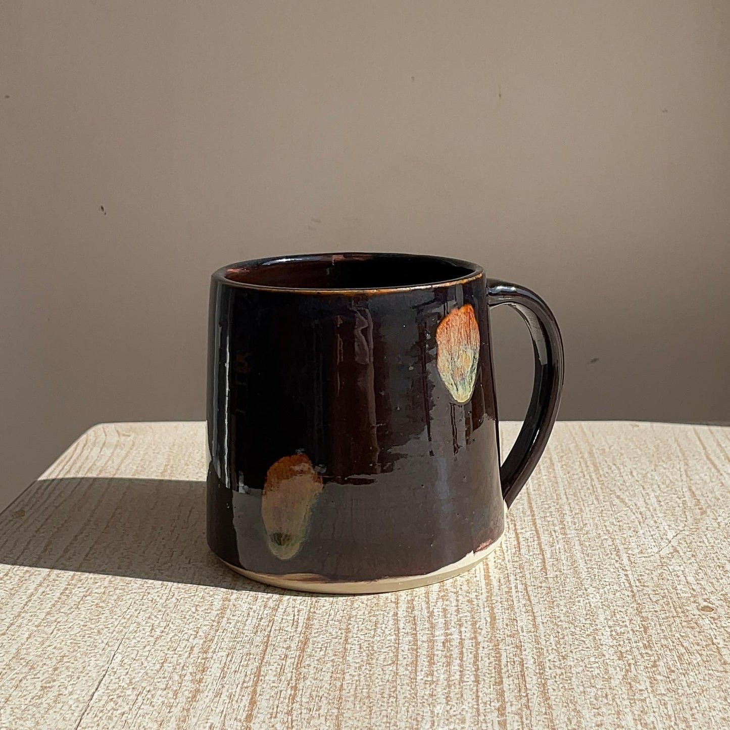 Black ceramic mug with abstract designs on a textured surface