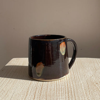 Black ceramic mug with abstract designs on a textured surface