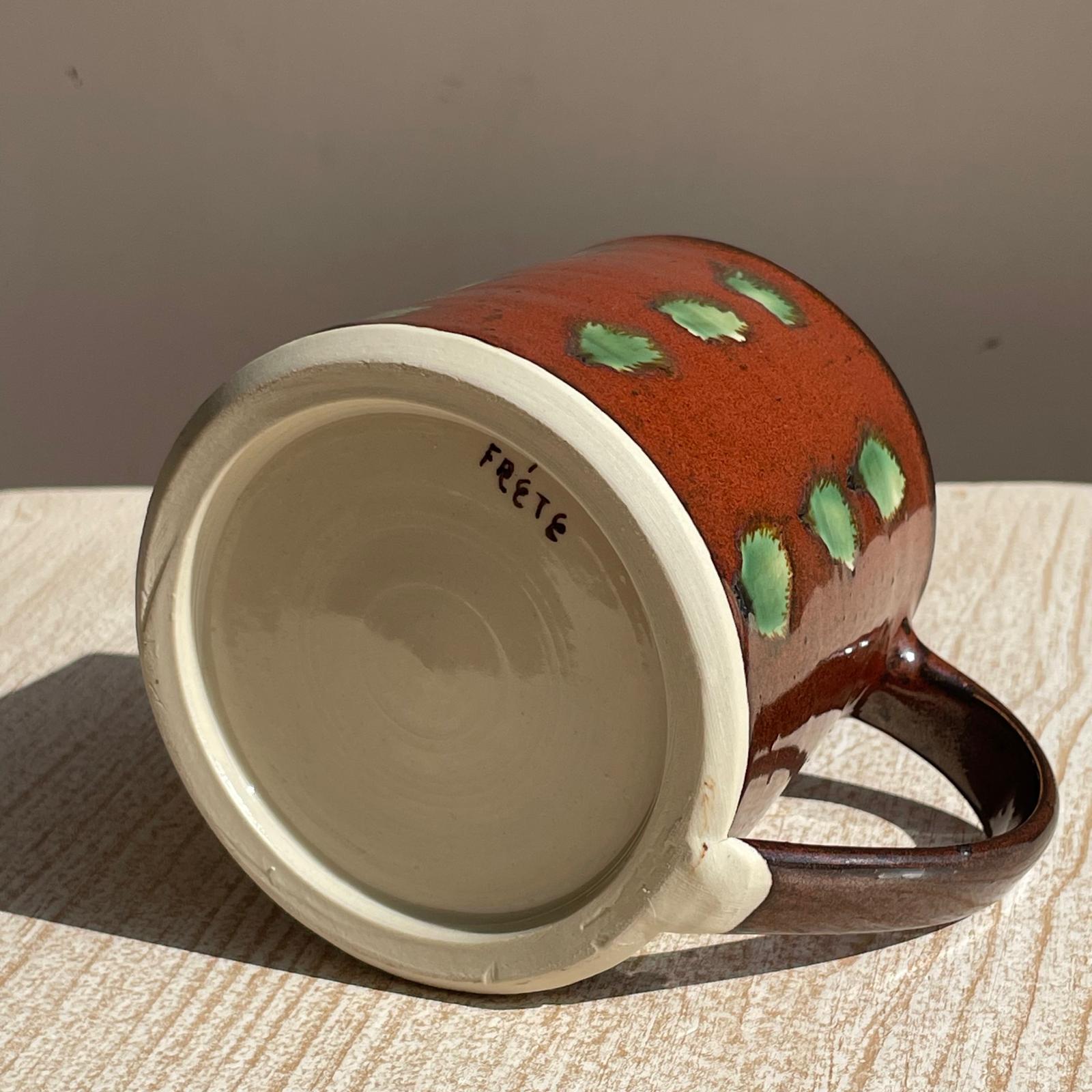 Ceramic mug with green polka dots on a wooden surface