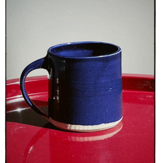 Blue ceramic mug on a red surface with a gray background
