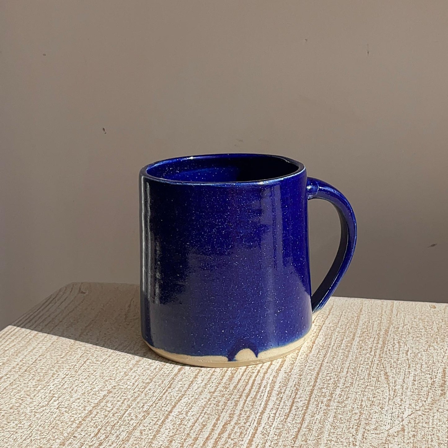 Blue ceramic mug on a textured surface with a neutral background