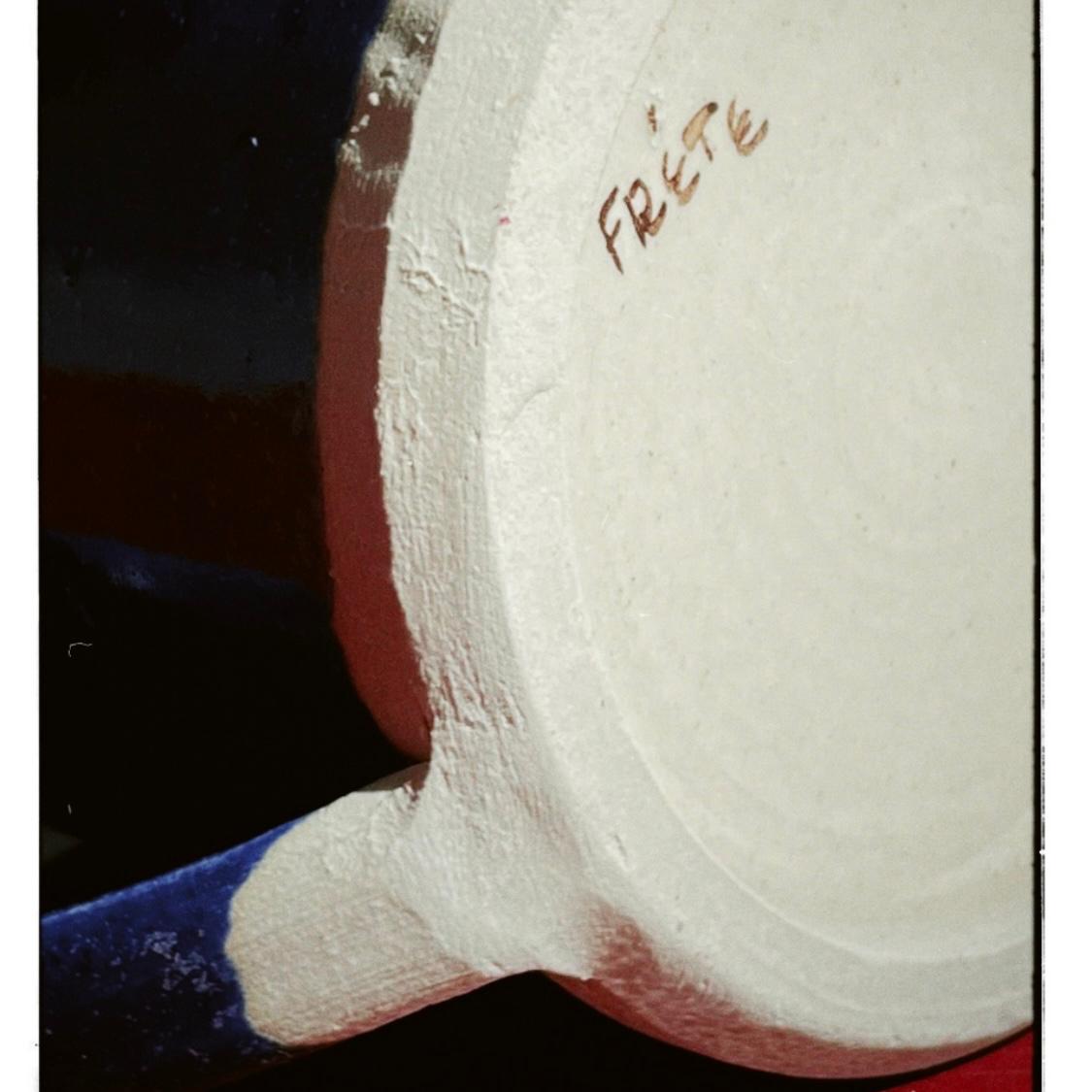 Close-up of a white ceramic pot with 'frete' branding on a dark background