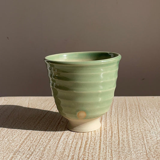 Green ceramic cup on a wooden surface with a brown background