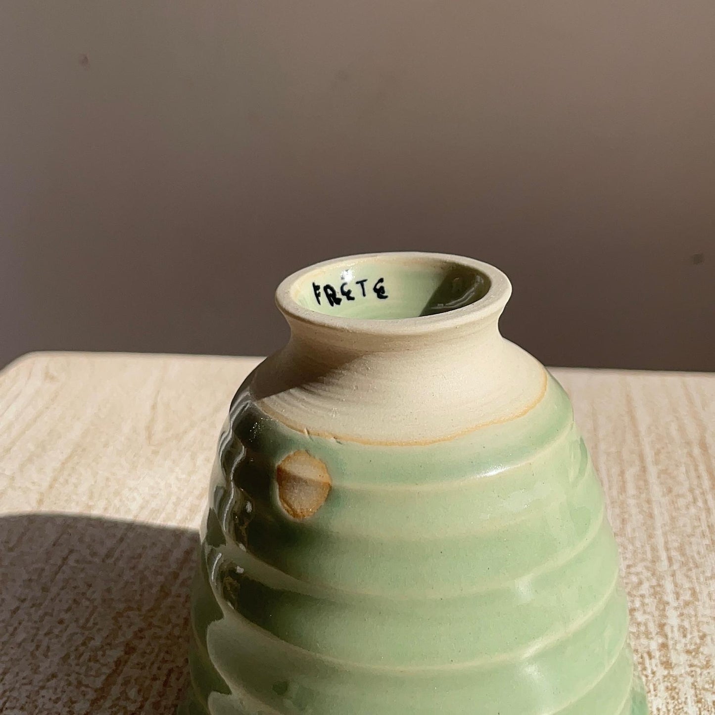 Green ceramic cup with textured surface on a neutral background