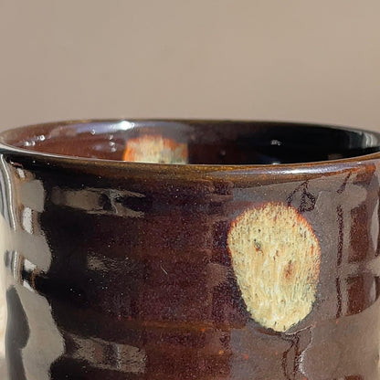 Close-up of a dark brown ceramic cup with a textured surface