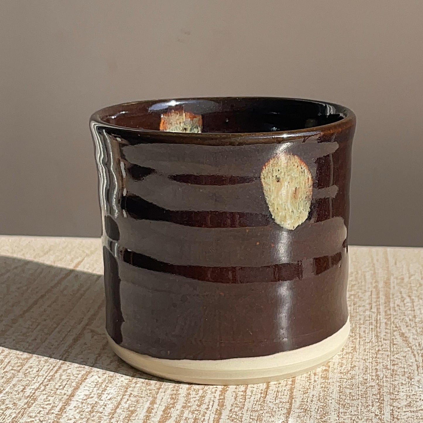 Brown ceramic pot with a textured surface on a wooden surface