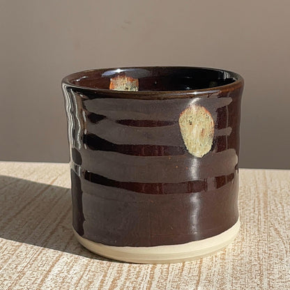 Brown ceramic pot with a textured surface on a wooden surface