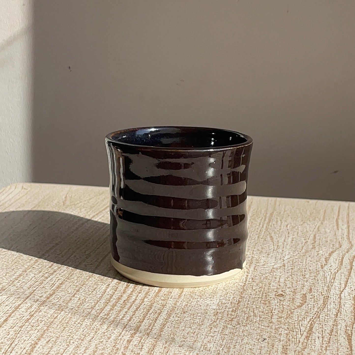Black ceramic cup with striped design on a wooden surface