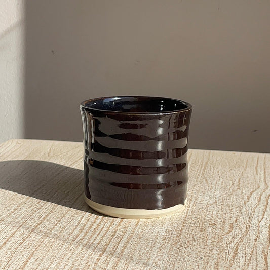 Black ceramic cup with striped design on a wooden surface