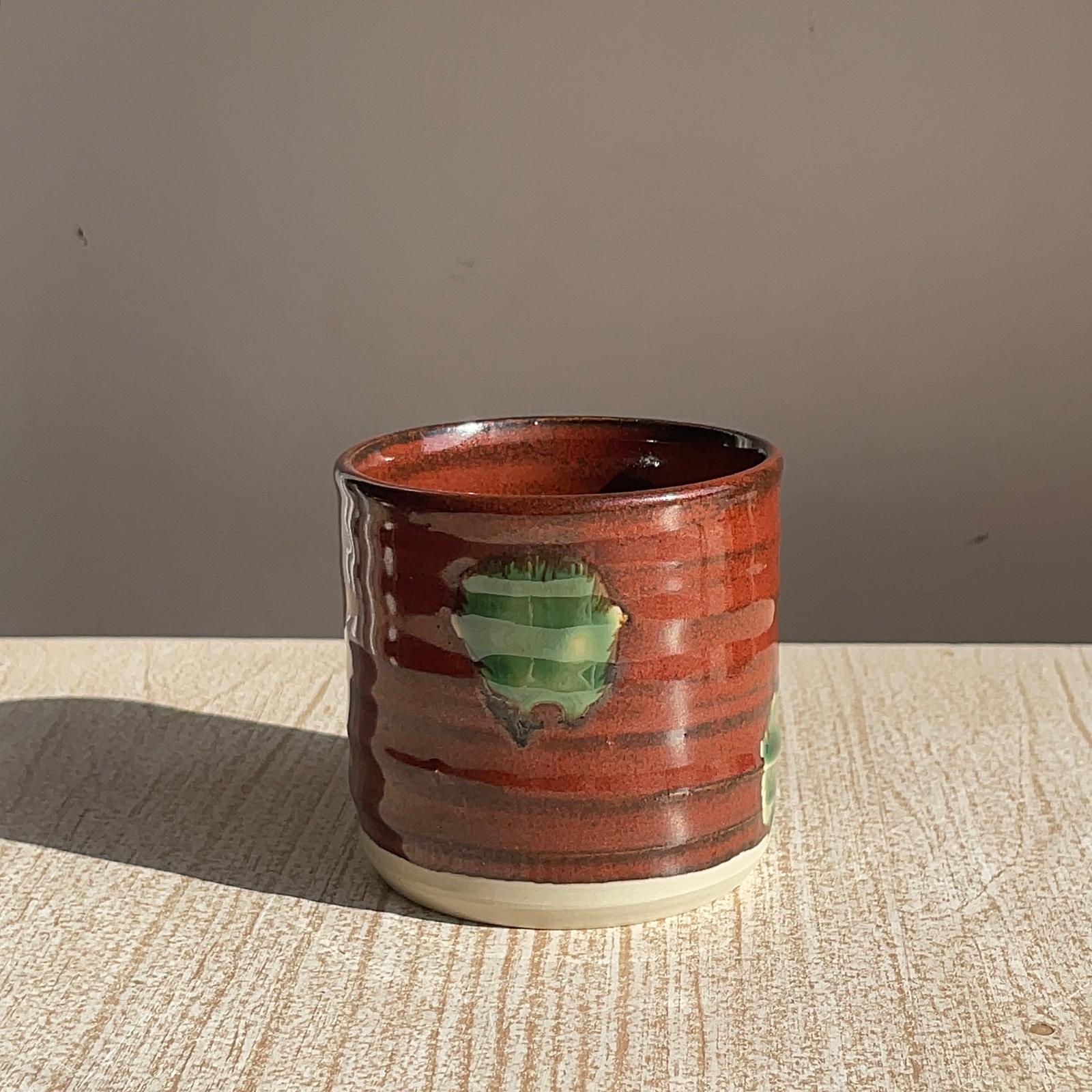Ceramic cup with a green heart design on a textured surface with a neutral background