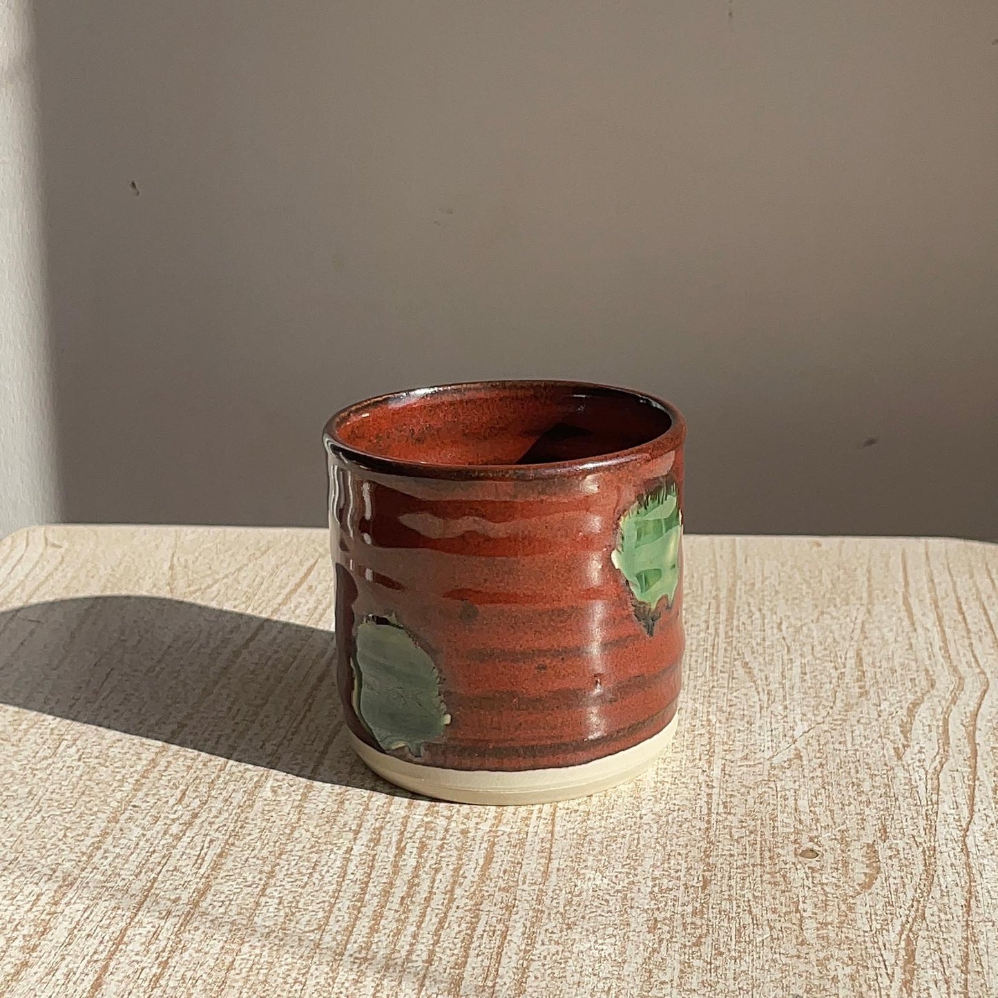 Ceramic cup with green accents on a wooden surface