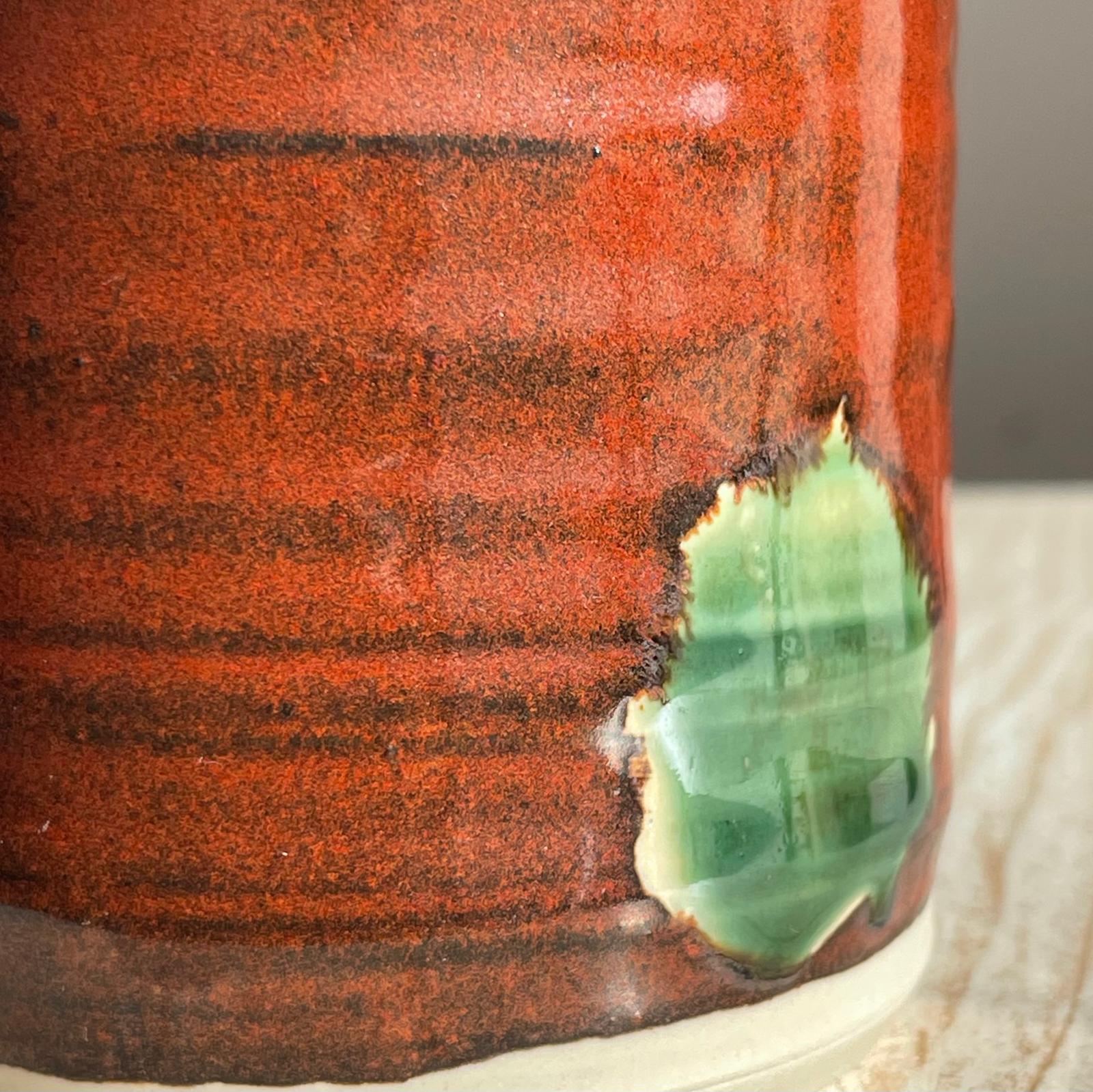 Close-up of a ceramic cup with a textured red-brown surface 