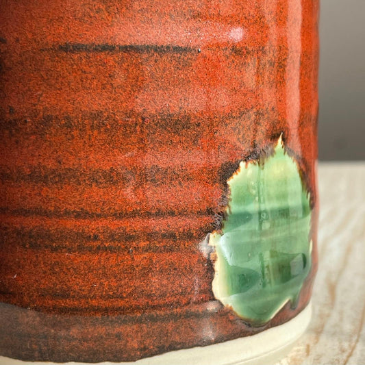 Close-up of a ceramic cup with a textured red-brown surface 