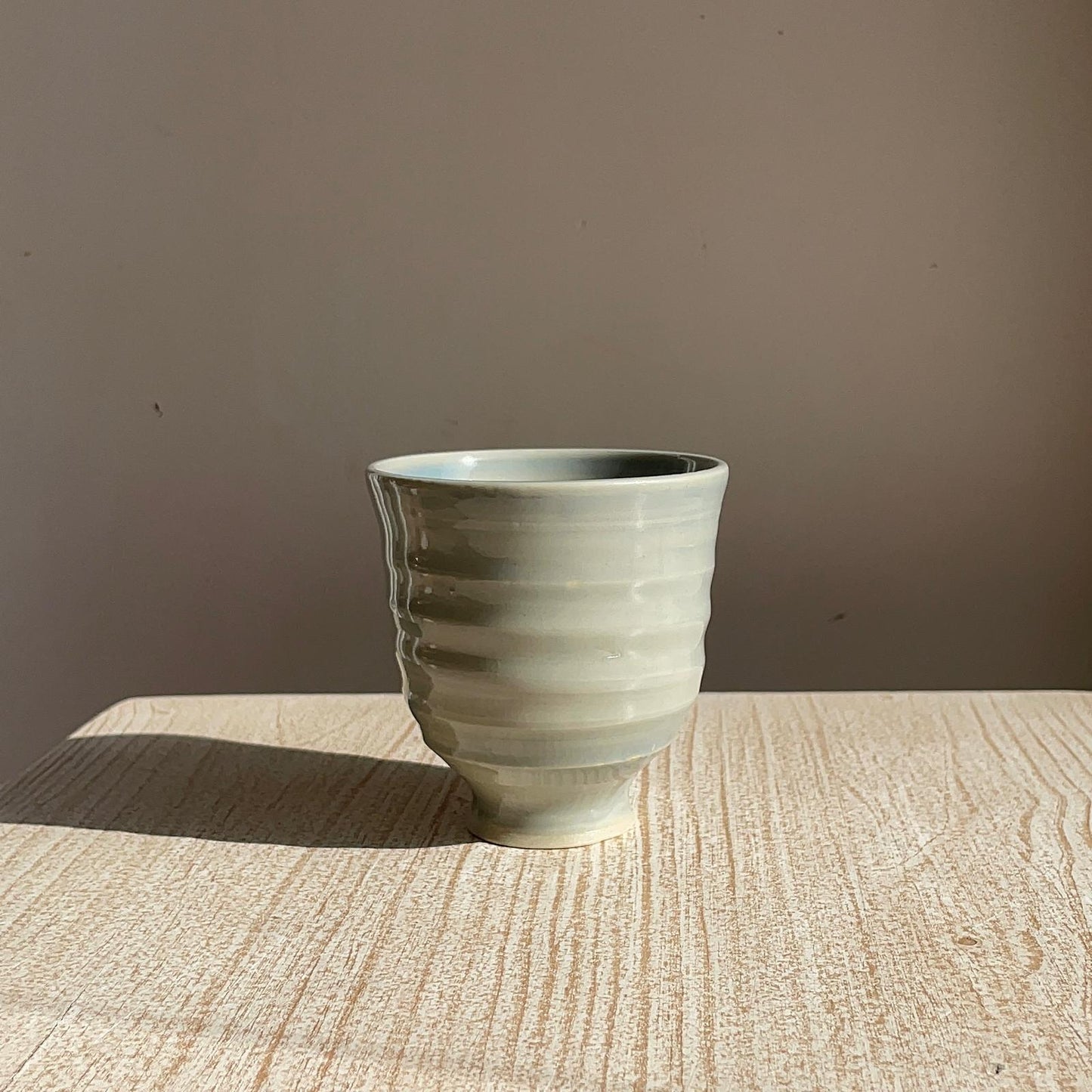 blue ceramic cup on a wooden surface with a brown background