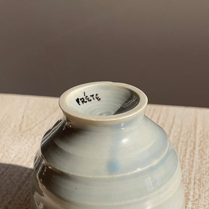 Ceramic cup with 'Frete' branding on a wooden surface