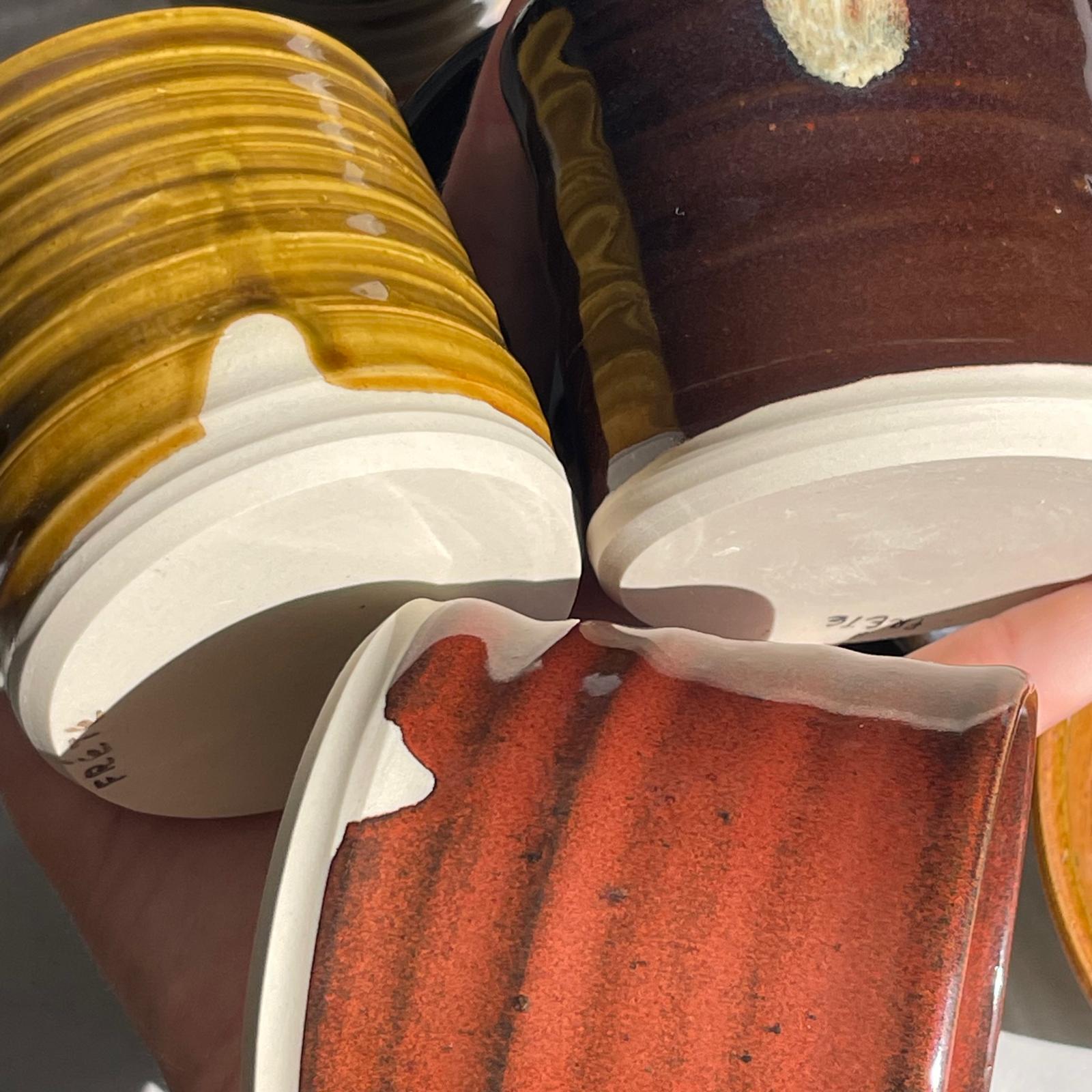 Close-up of ceramic cups with different glaze colors.