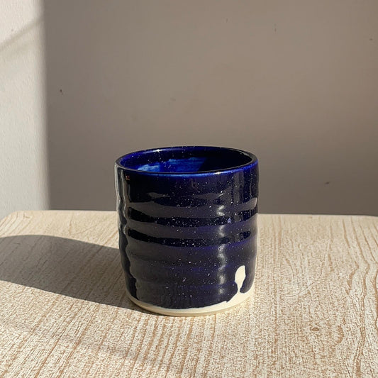 Blue ceramic cup on a wooden surface with a neutral background