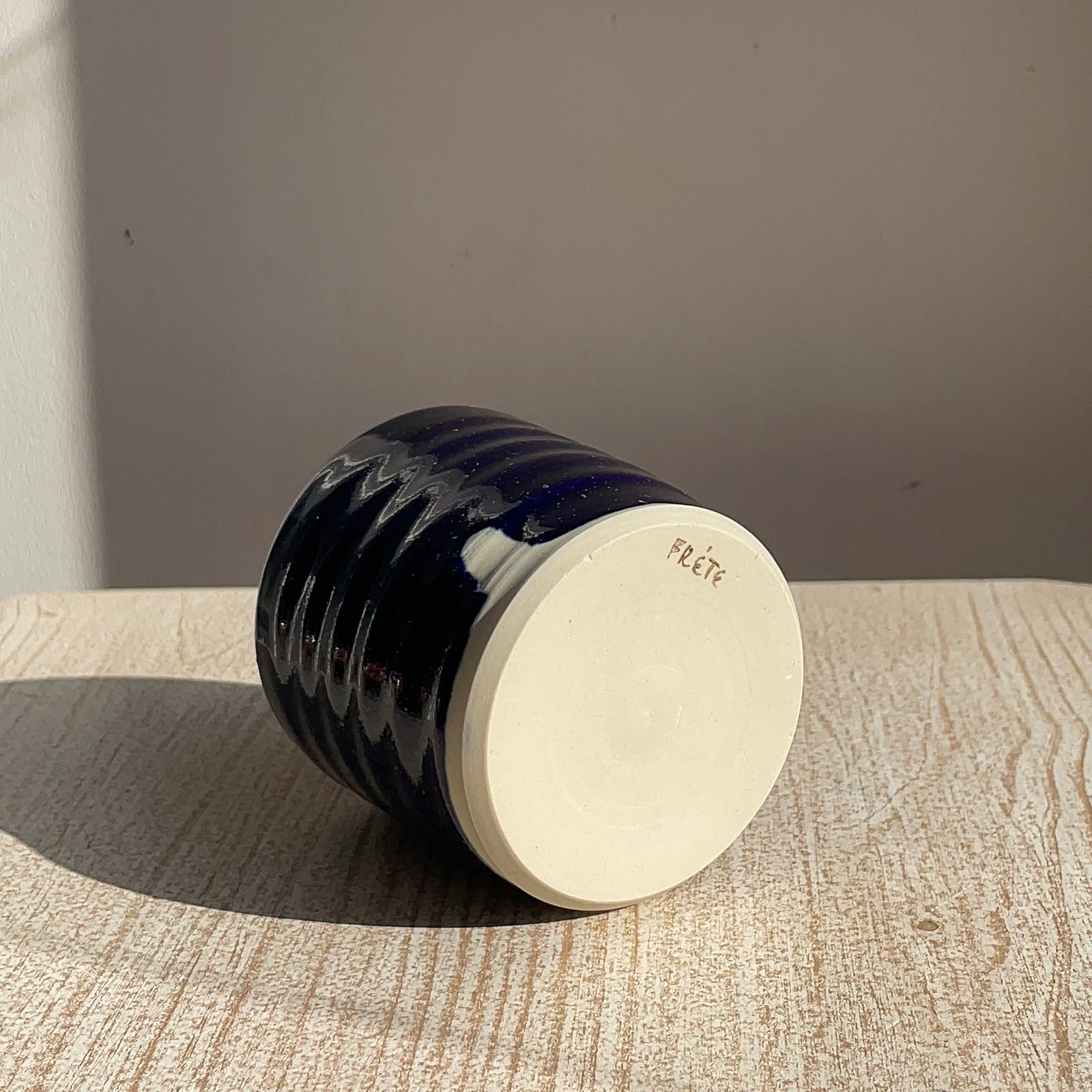 blue ribbed ceramic cup on a wooden surface with a neutral background
