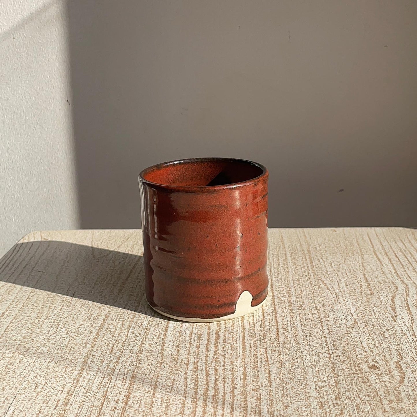 Red ceramic cup on a textured surface with a neutral background