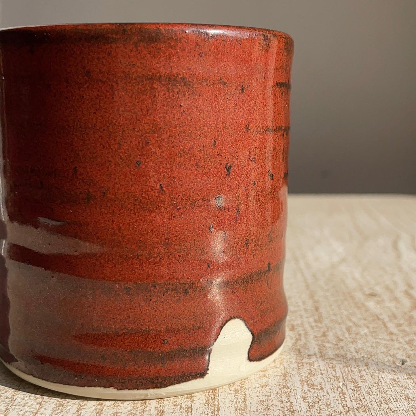 Red ceramic cup on a textured surface with a neutral background
