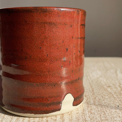 Red ceramic cup on a textured surface with a neutral background
