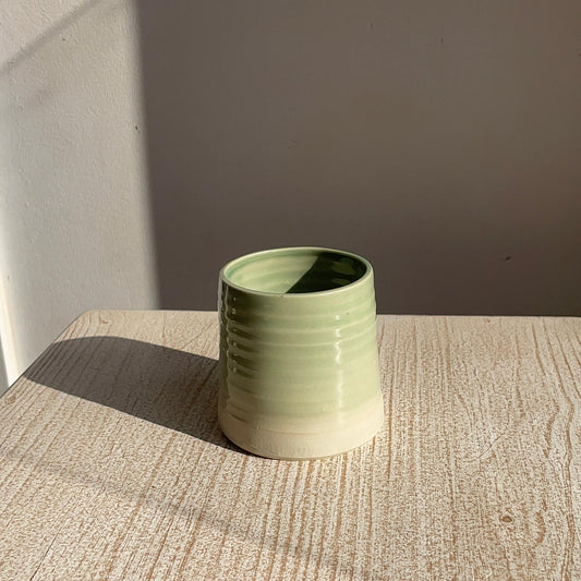Green ceramic cup on a textured surface with a neutral background