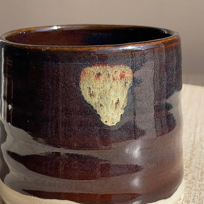black ceramic mug with a natural stone embedded on a neutral background