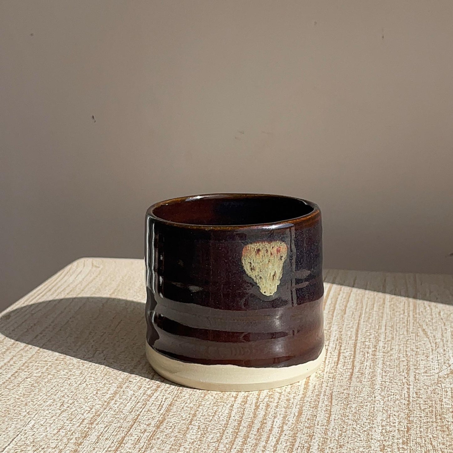 black ceramic cup with a textured design on a beige surface