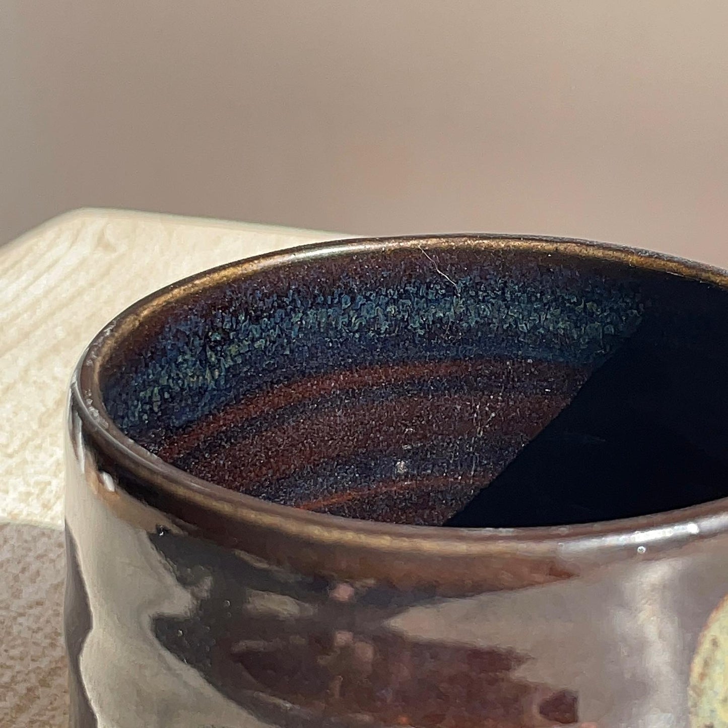 Close-up of a dark ceramic cup with a textured interior on a neutral background