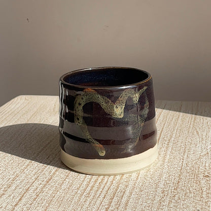 Ceramic cup with decorative design on a textured surface