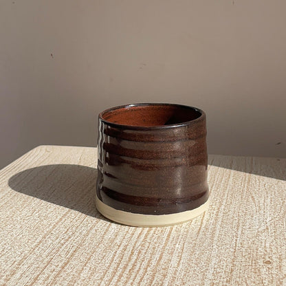 red ceramic cup on a textured surface with a neutral background