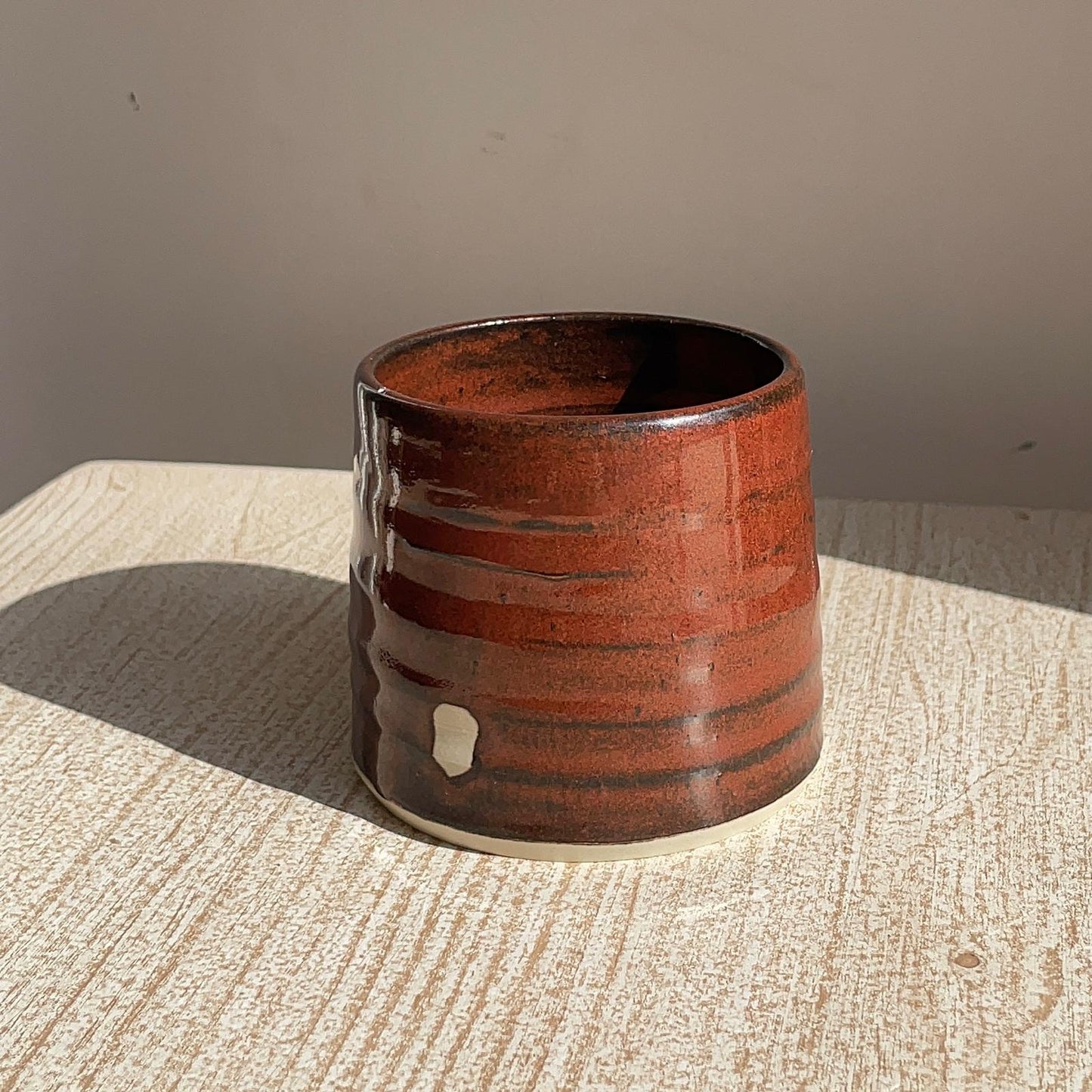 red ceramic cup on a textured surface with a neutral background