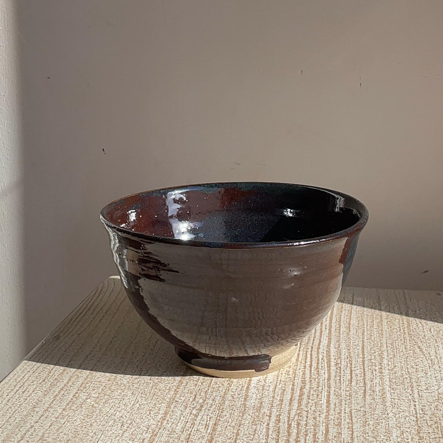 Brown ceramic bowl on a textured surface with a neutral background