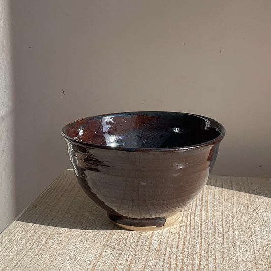 Brown ceramic bowl on a textured surface with a neutral background