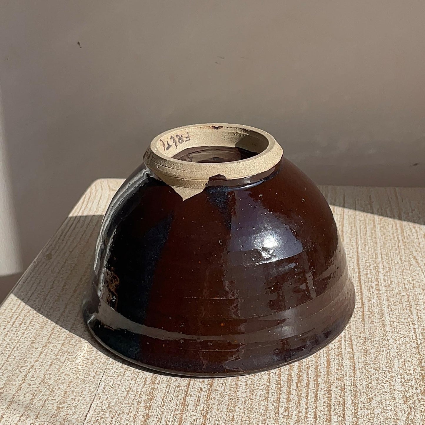Brown ceramic bowl on a textured surface with a neutral background