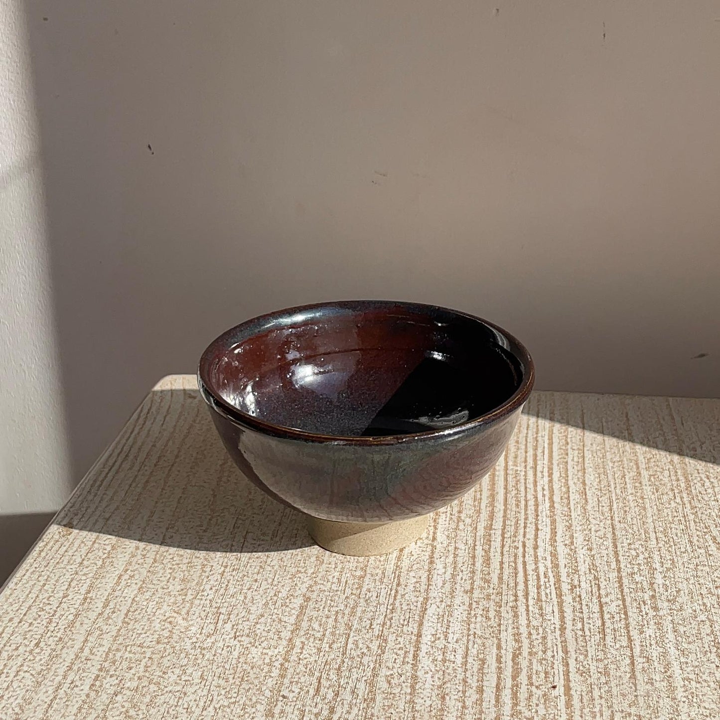 Brown ceramic bowl on a textured surface with a neutral background
