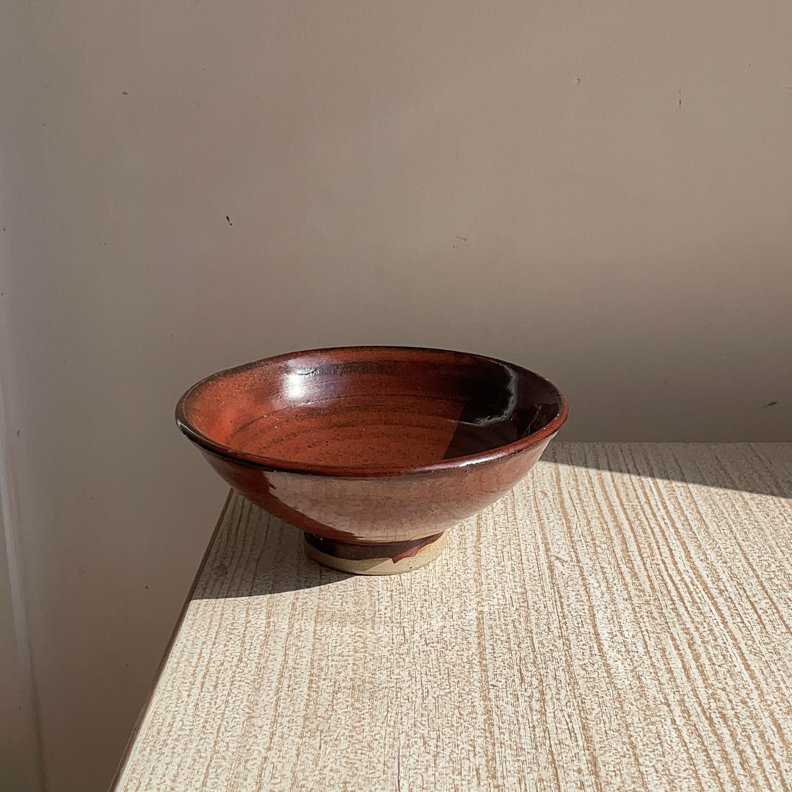 red ceramic bowl on a textured surface with a plain wall background