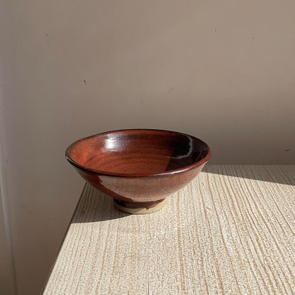 red ceramic bowl on a textured surface with a plain wall background
